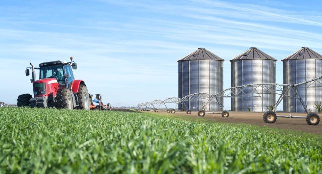 Agriculture and food production concept with tractor machine silos and irrigation system. Agriculture and food production concept with tractor machine silos and irrigation system.